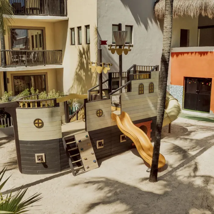 A sandy kids' play area featuring a pirate ship-themed playground with a slide.