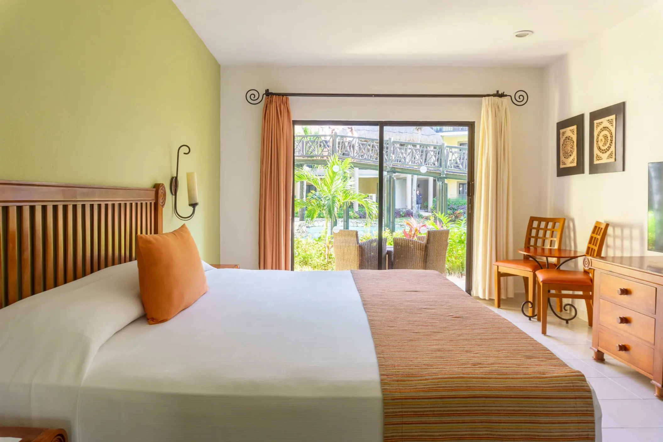 A bright suite with a large bed, garden view balcony, and traditional wooden furniture.