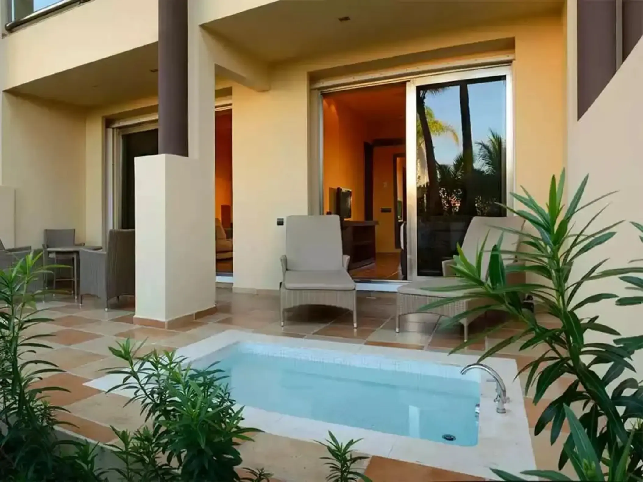 A suite's patio with a private hot tub, lounge chairs, and lush greenery.