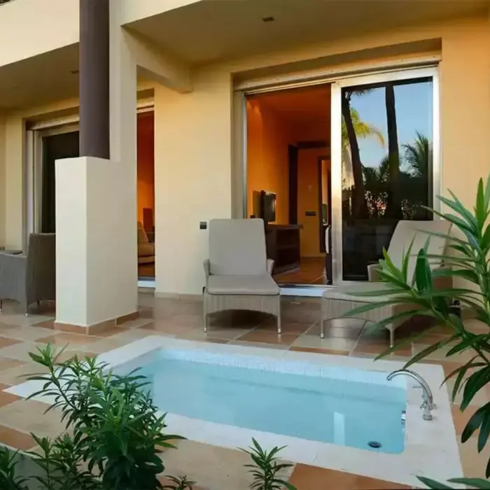 A suite's patio with a private hot tub, lounge chairs, and lush greenery.