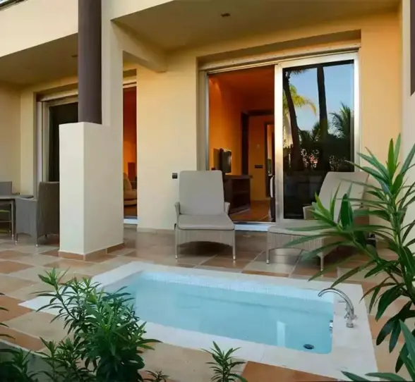 A suite's patio with a private hot tub, lounge chairs, and lush greenery.