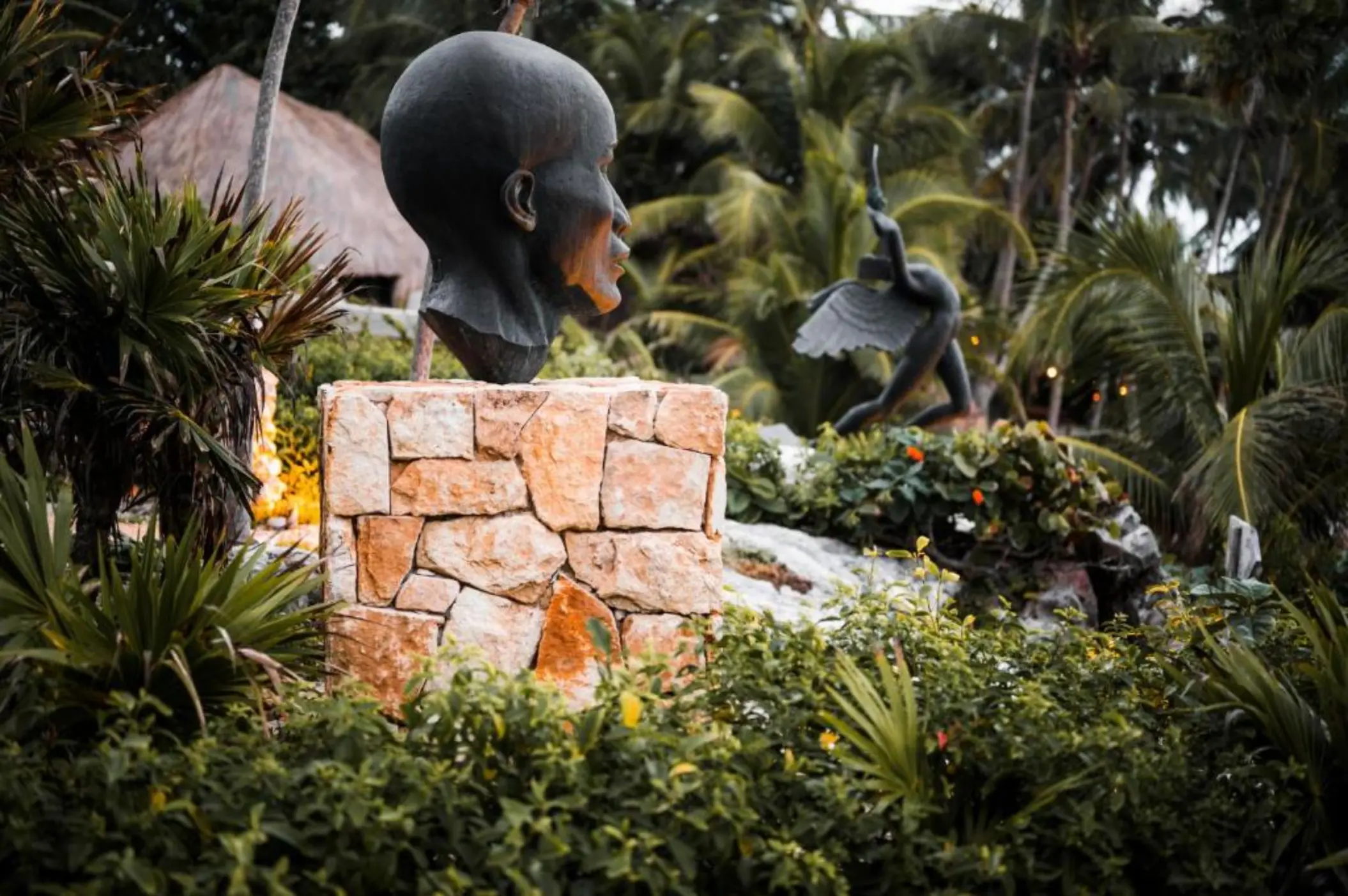 Large, unique art sculptures placed amidst lush tropical plants at the resort.