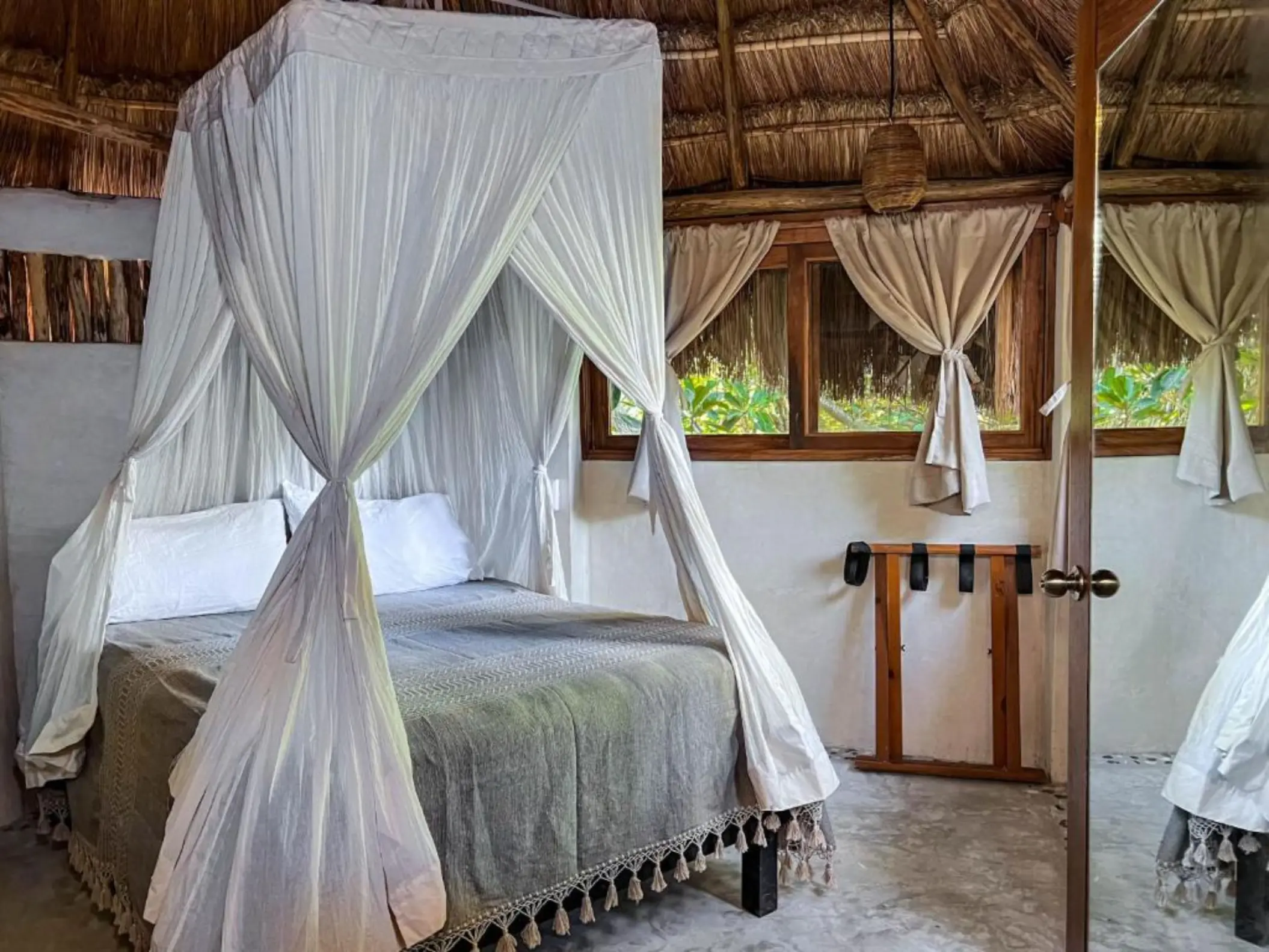 A cozy economic suite featuring a canopy bed, a thatched roof, and rustic decor.