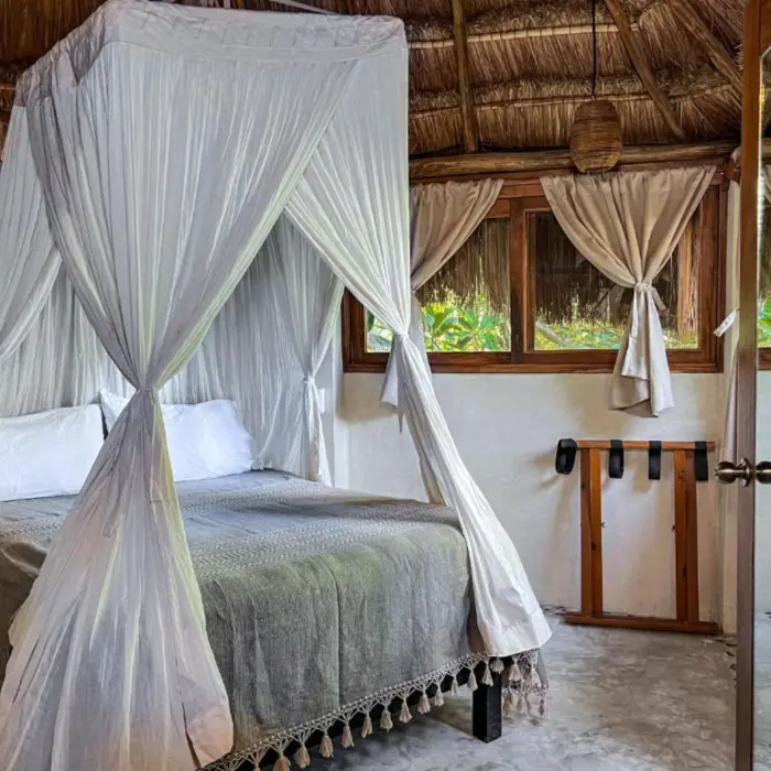 A cozy economic suite featuring a canopy bed, a thatched roof, and rustic decor.