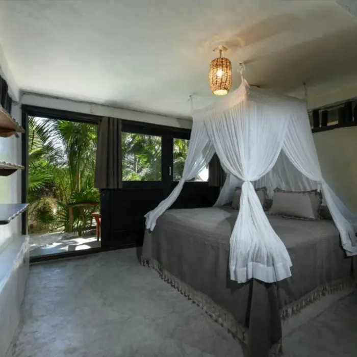 A tranquil garden view king room with a canopy bed and a direct outdoor access to lush greenery.