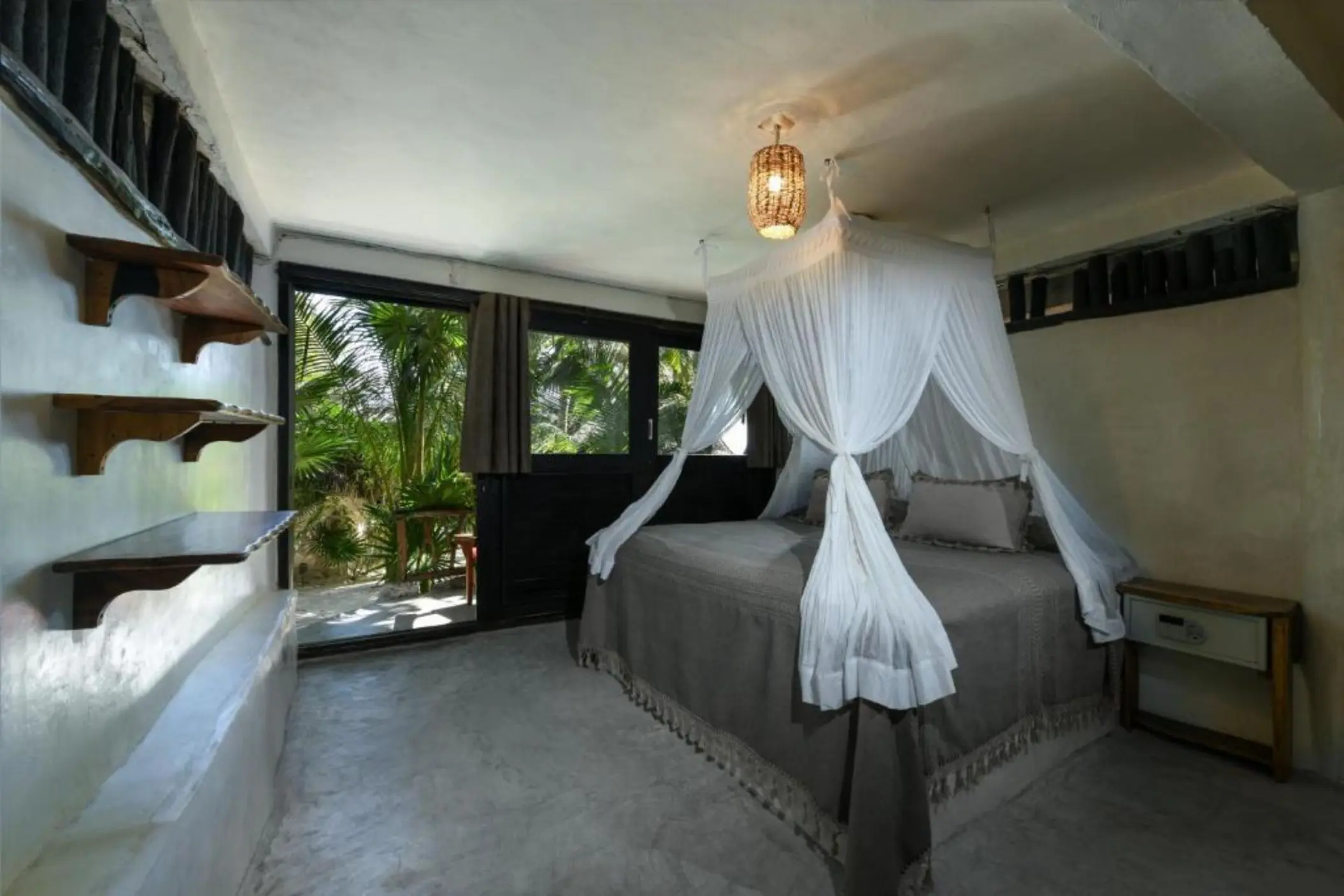 A tranquil garden view king room with a canopy bed and a direct outdoor access to lush greenery.