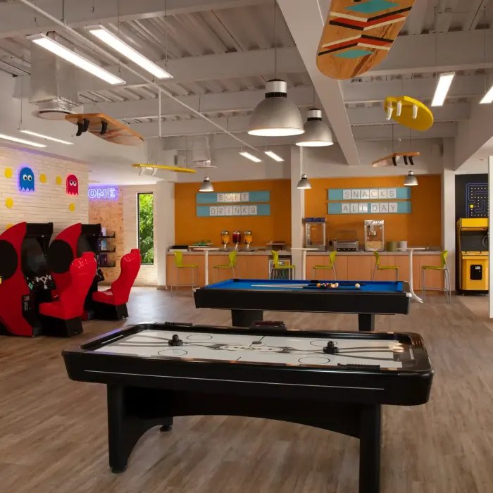 Lively teen zone featuring arcade games, air hockey, pool table, snack bar, and vibrant, urban-inspired decor.