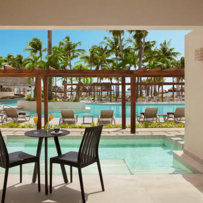 Pool-view deluxe room with sofa and terrace, ideal for relaxing in tropical style.