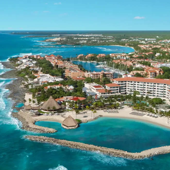 Aerial view of Dreams Aventuras resort in Riviera Maya with marina, beachfront hotels, and protected lagoon.