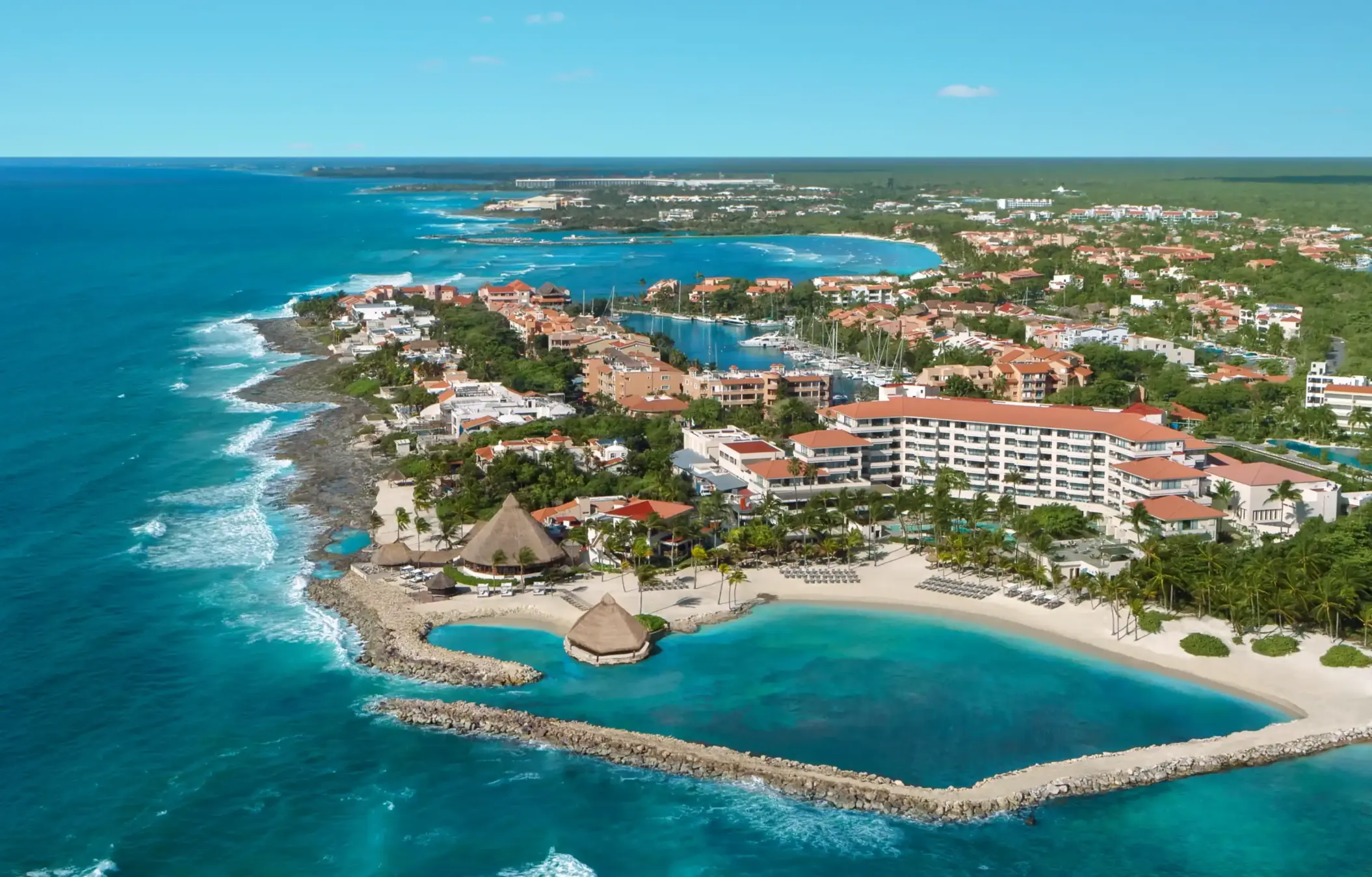 Aerial view of Dreams Aventuras resort in Riviera Maya with marina, beachfront hotels, and protected lagoon.