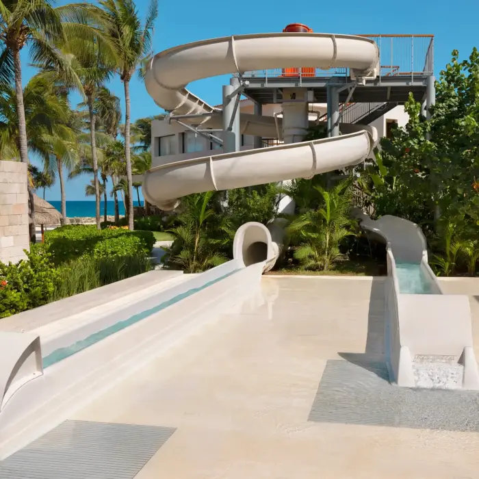 Outdoor water slide surrounded by palm trees and tropical plants, perfect for family fun under the sun.