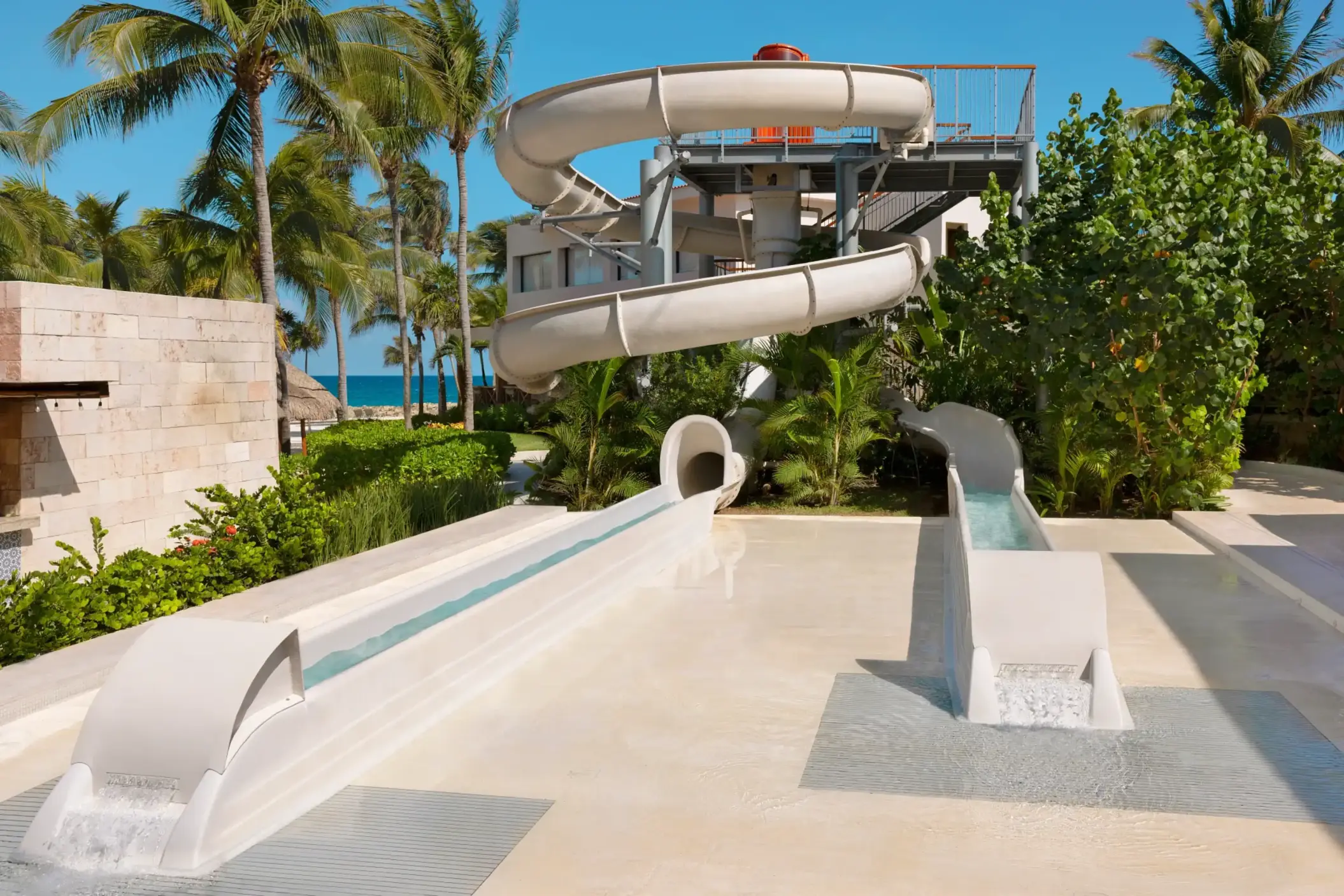 Outdoor water slide surrounded by palm trees and tropical plants, perfect for family fun under the sun.