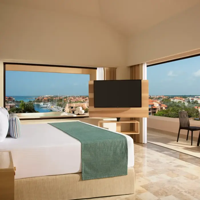 Cozy marina view room with elegant wood accents and a sunlit private balcony at Dreams Puerto Aventuras.