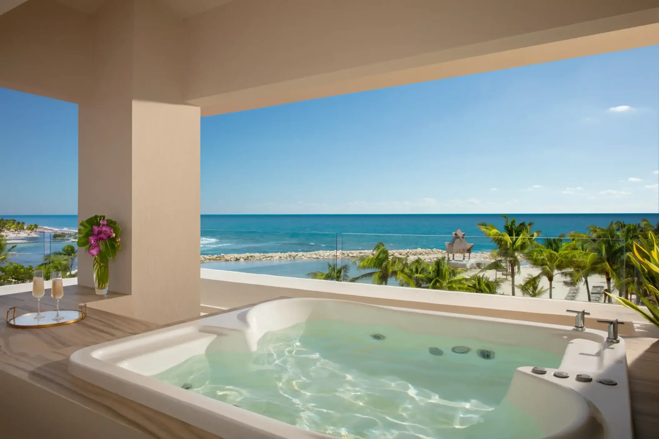 Private outdoor hot tub on a spacious terrace overlooking the turquoise Caribbean Sea and palm-lined beach.