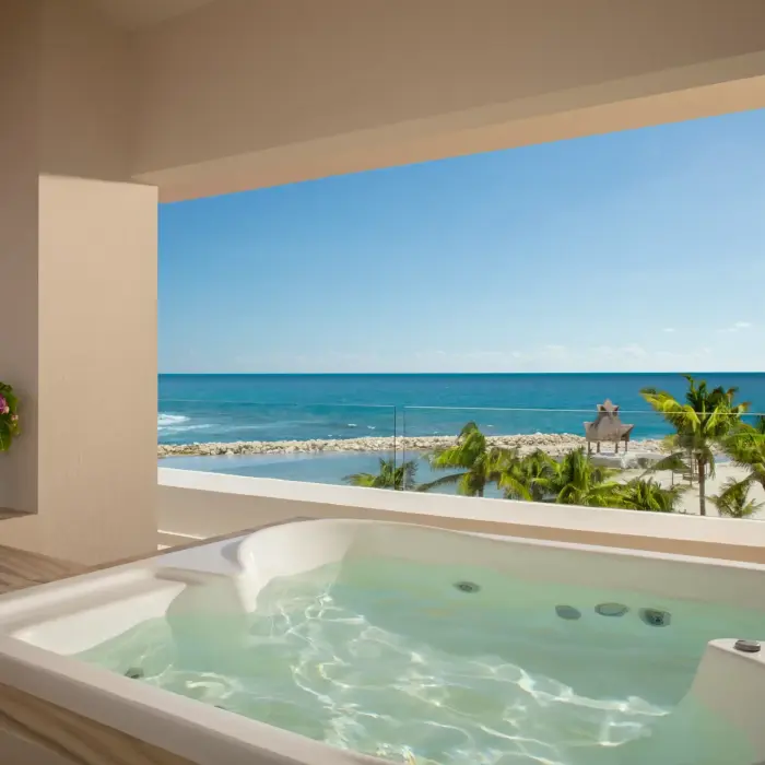 Private outdoor hot tub on a spacious terrace overlooking the turquoise Caribbean Sea and palm-lined beach.