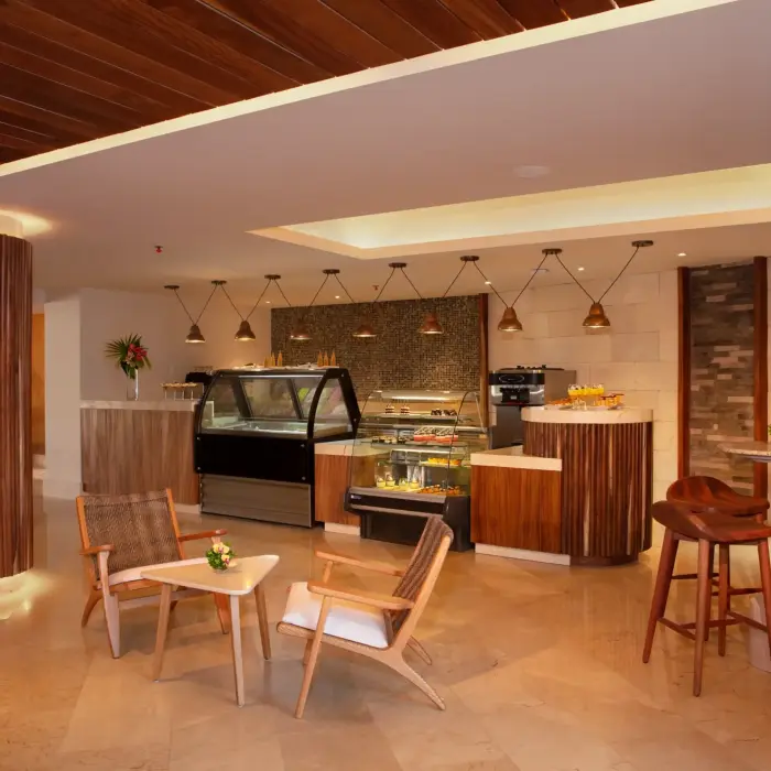 Chic café with wooden finishes, dessert display cases, cozy lounge seating, and warm, modern lighting.