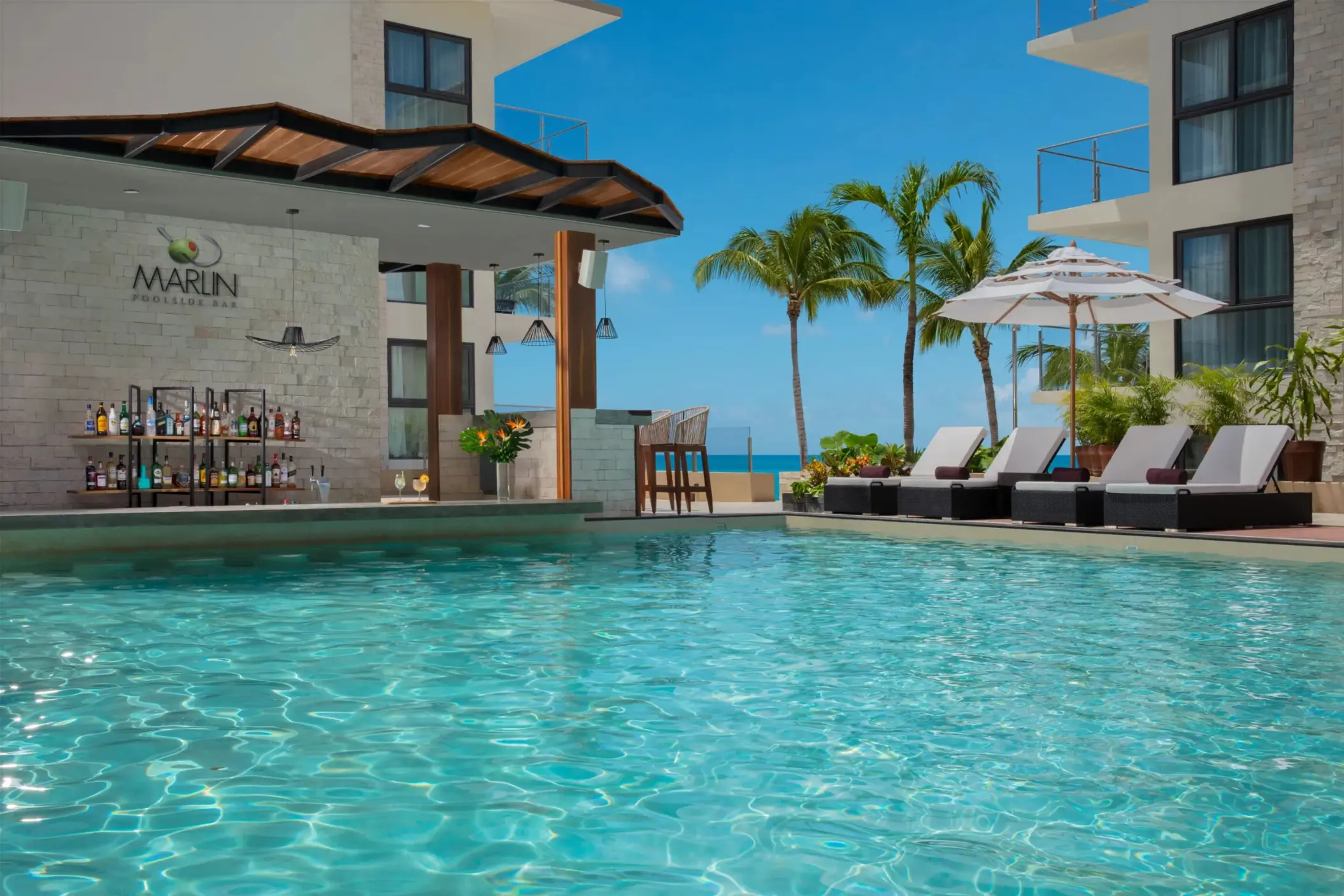 Marlin swim-up bar with tropical cocktails, shaded loungers, palm trees, and poolside relaxation.