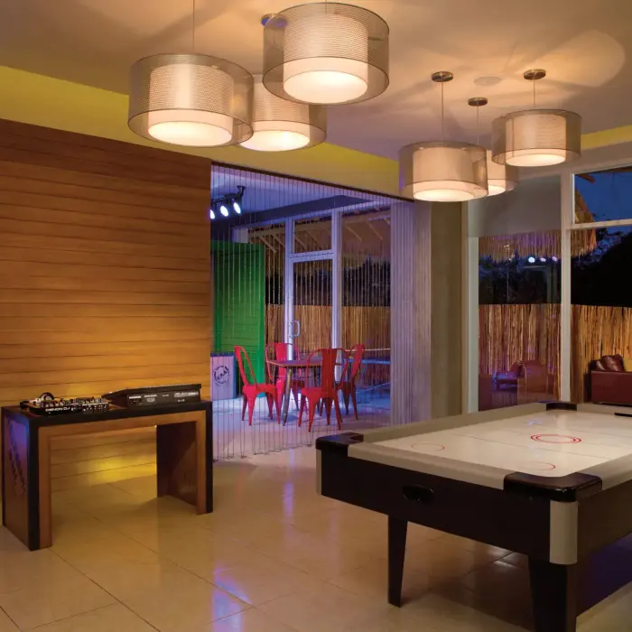 Core Zone teen lounge with DJ table, air hockey, colorful seating, and relaxed indoor vibe.