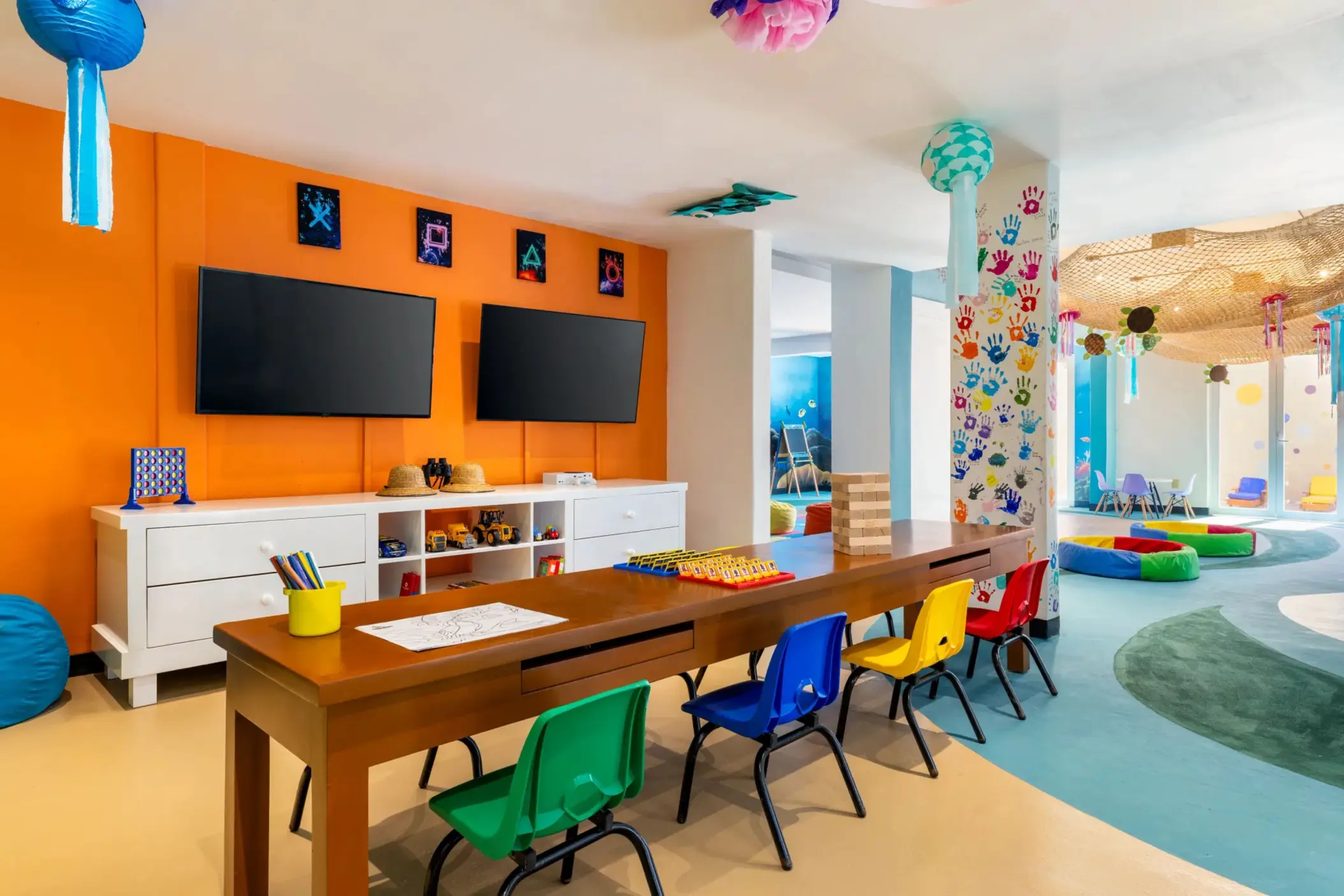 Colorful Explorer’s Club room with games, TV screens, mini chairs, and playful jellyfish decorations.