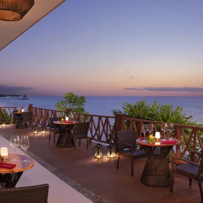 Romantic terrace dining at sunset with candlelit tables and panoramic ocean views at Annatto restaurant.