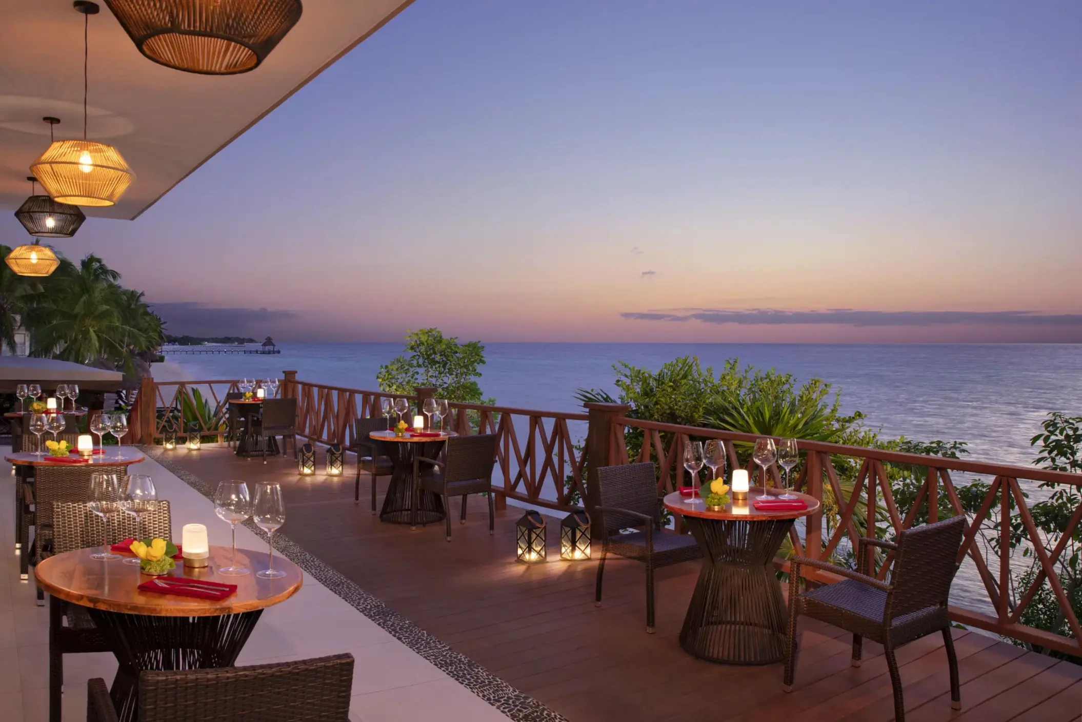 Romantic terrace dining at sunset with candlelit tables and panoramic ocean views at Annatto restaurant.