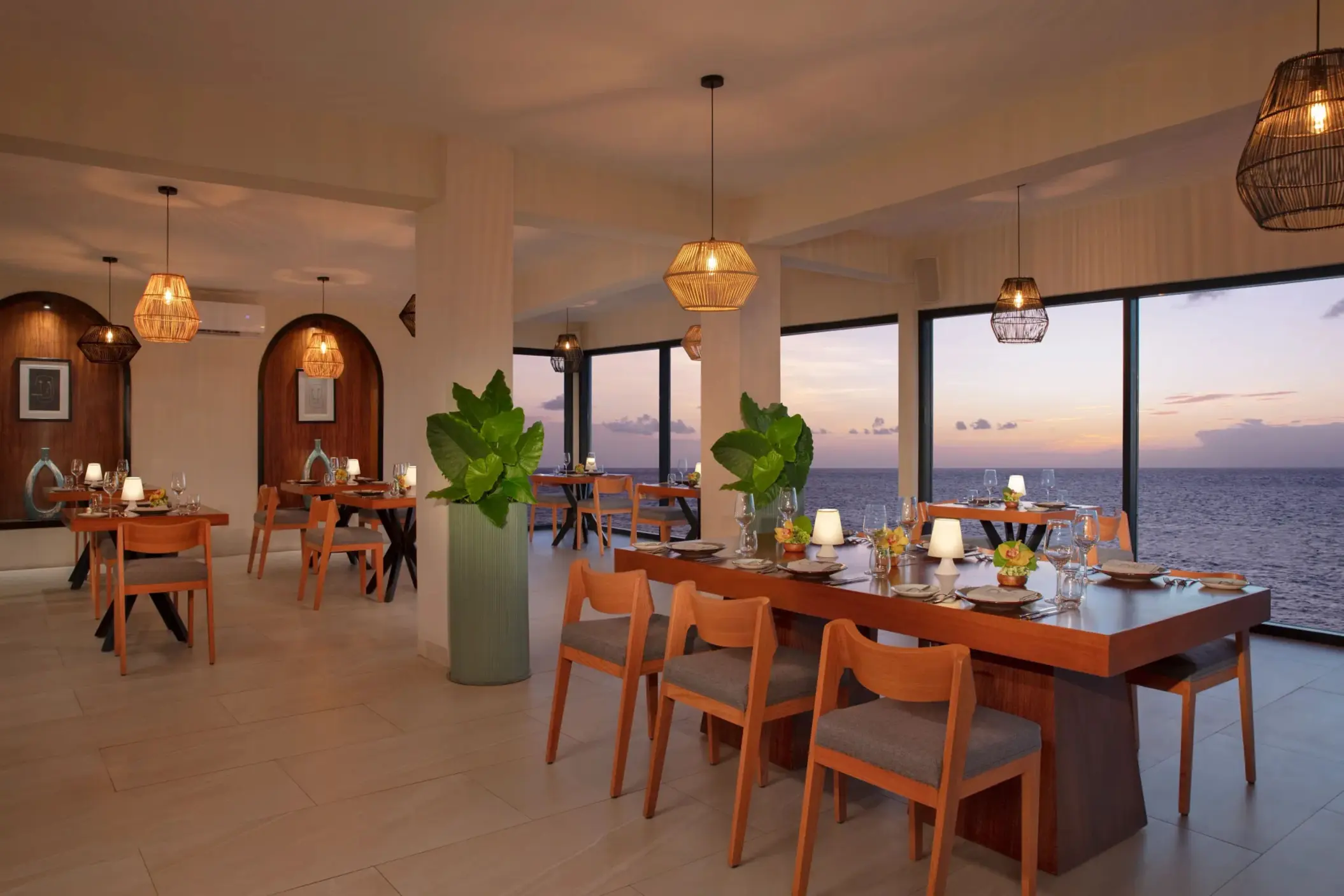 Chic indoor dining at Olio restaurant with soft lighting, ocean views, and stylish wooden furnishings.