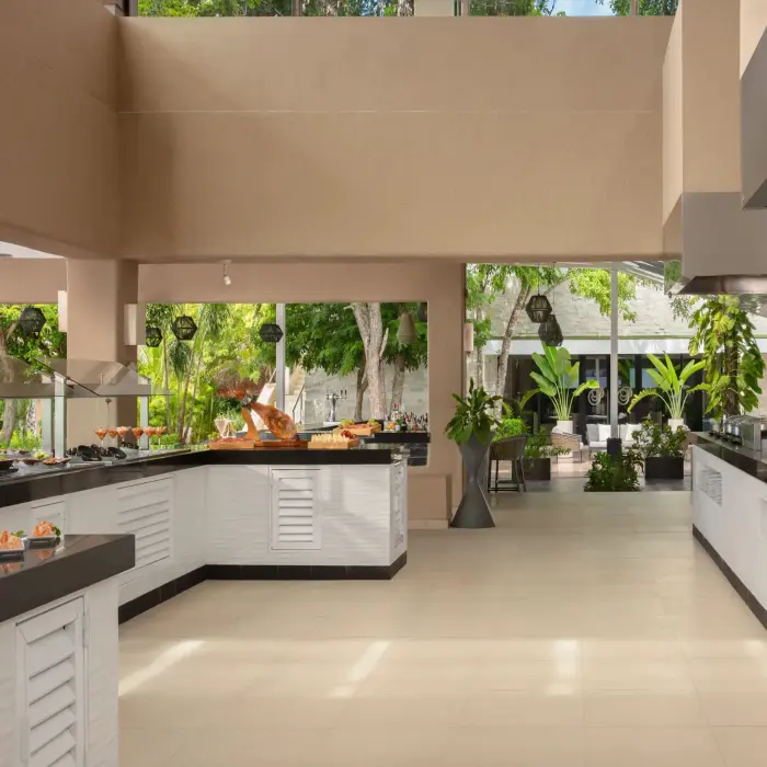 Spacious buffet setup at World Café with modern counters, tropical plants, and daylight-filled dining area.