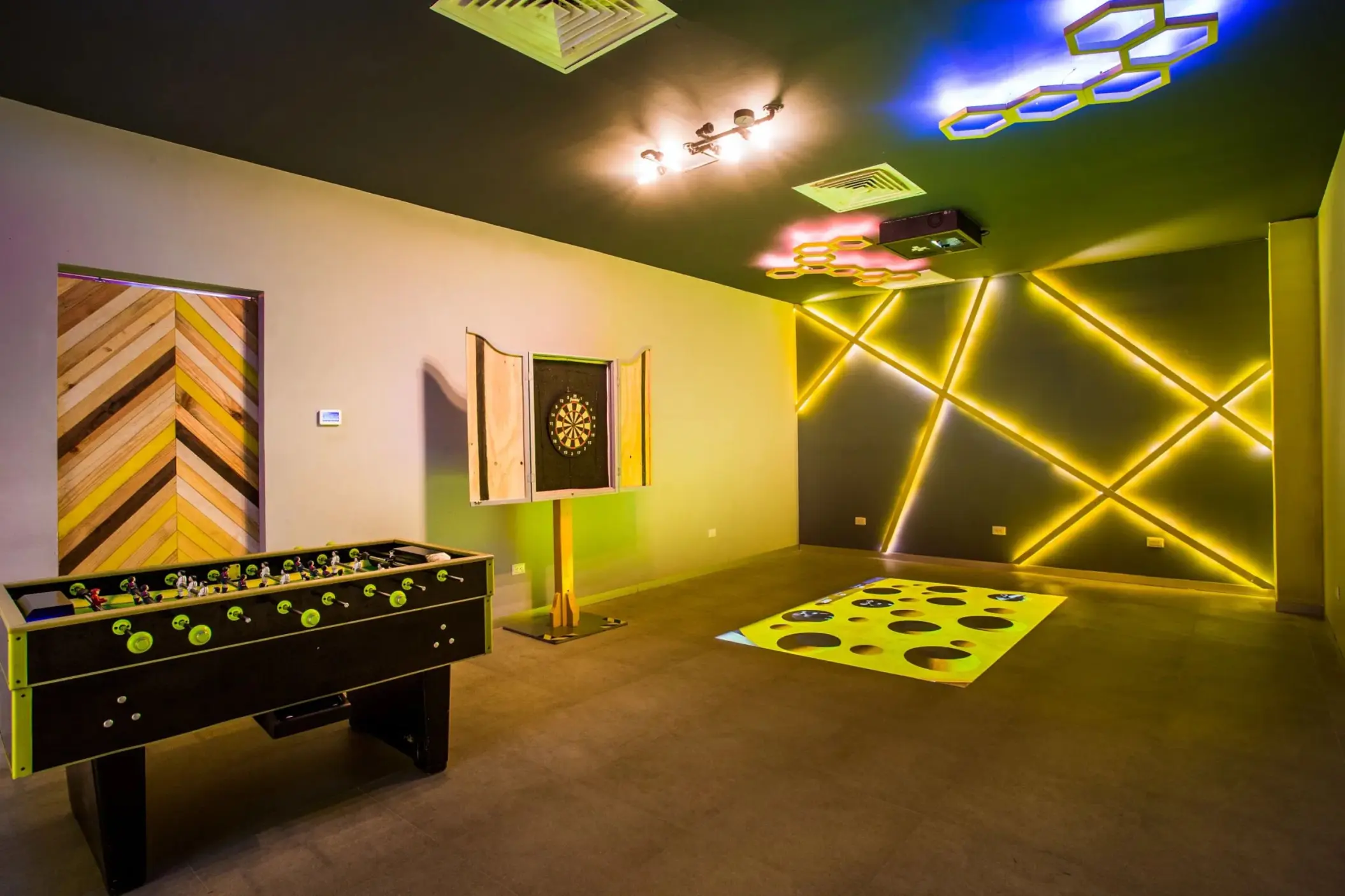 Interactive game room with foosball table, dart board, and light-up wall designs perfect for teen entertainment.