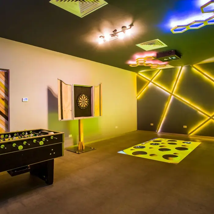 Interactive game room with foosball table, dart board, and light-up wall designs perfect for teen entertainment.