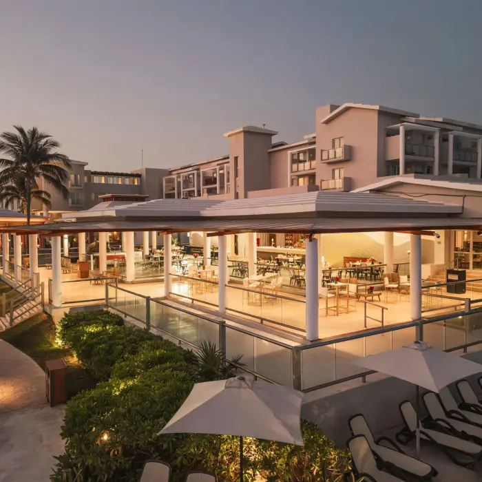 Evening view of open-air restaurant at Dreams Jade Resort, surrounded by lush landscaping and soft lighting.