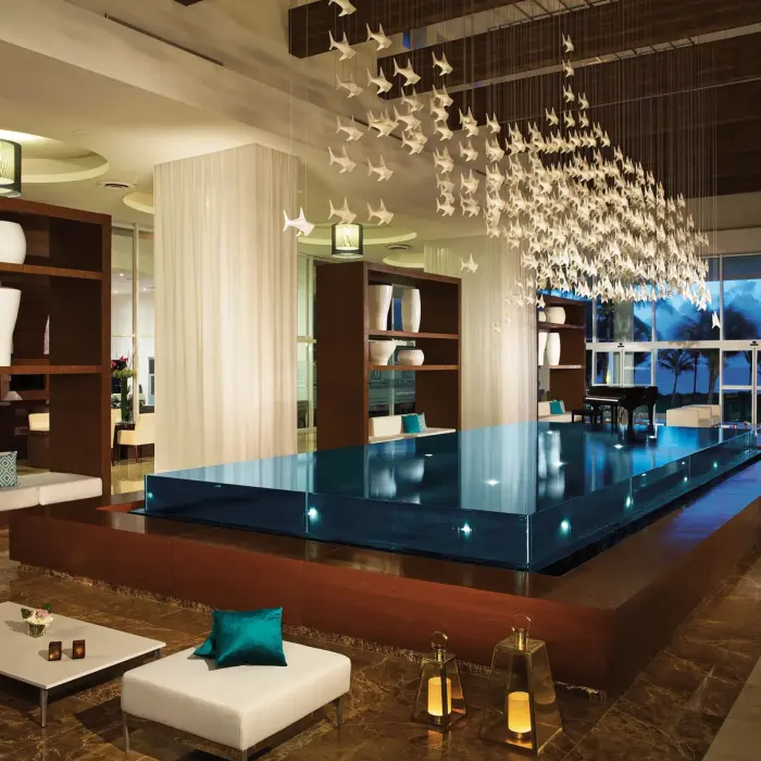 Modern lobby with chic seating, floating platform, lanterns, and ceiling installation of white hanging birds.