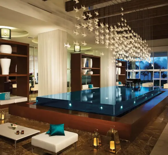 Modern lobby with chic seating, floating platform, lanterns, and ceiling installation of white hanging birds.
