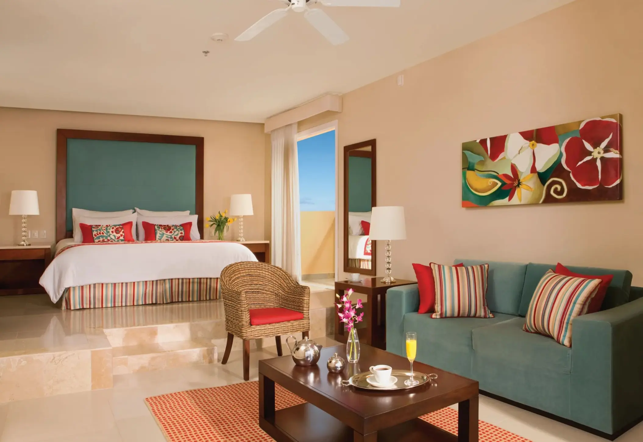 Spacious junior suite with king bed, striped accents, sitting area, and balcony with ocean glimpses.