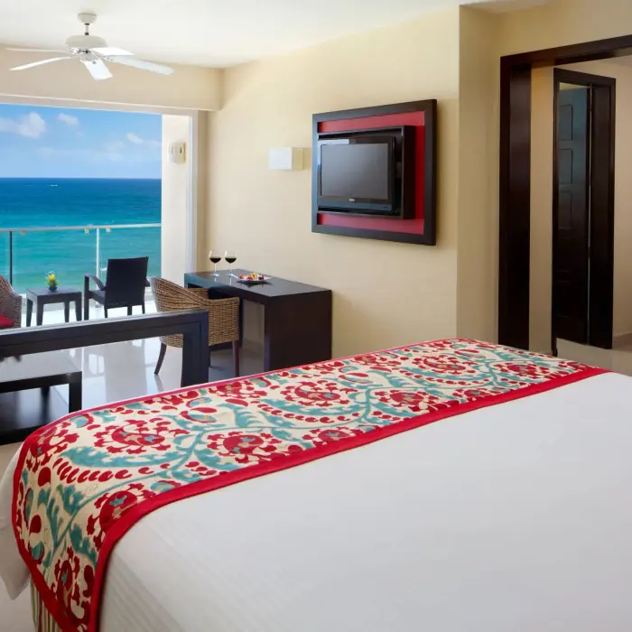 King bed suite with stylish decor, flat-screen TV, and private balcony showcasing stunning ocean views.