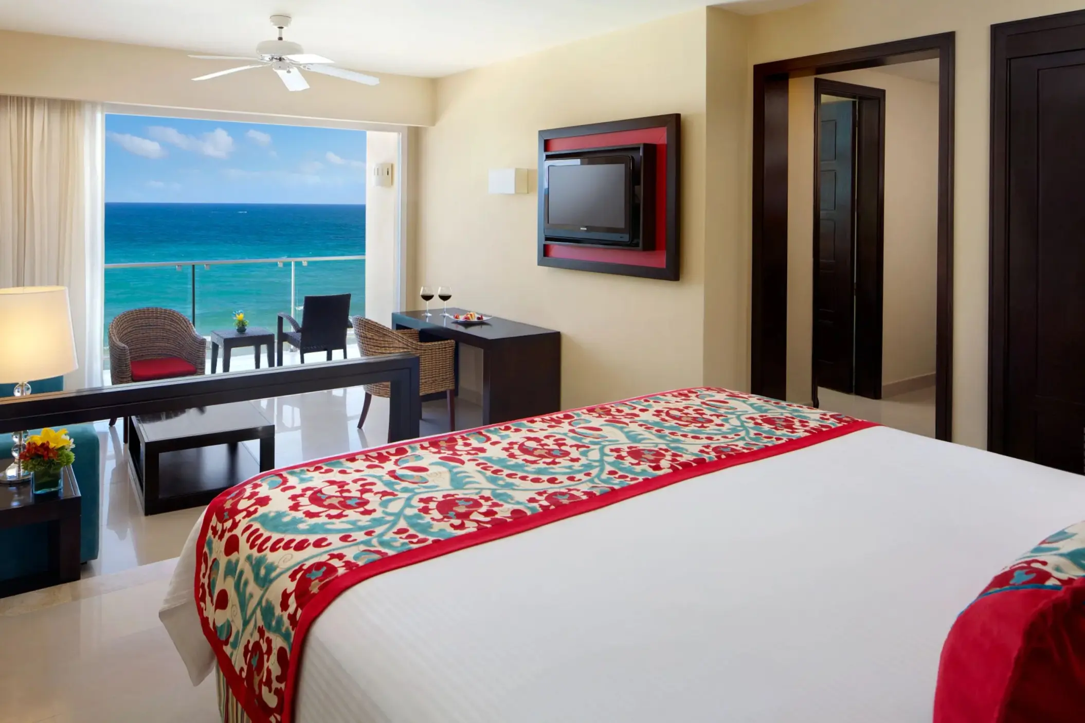 King bed suite with stylish decor, flat-screen TV, and private balcony showcasing stunning ocean views.