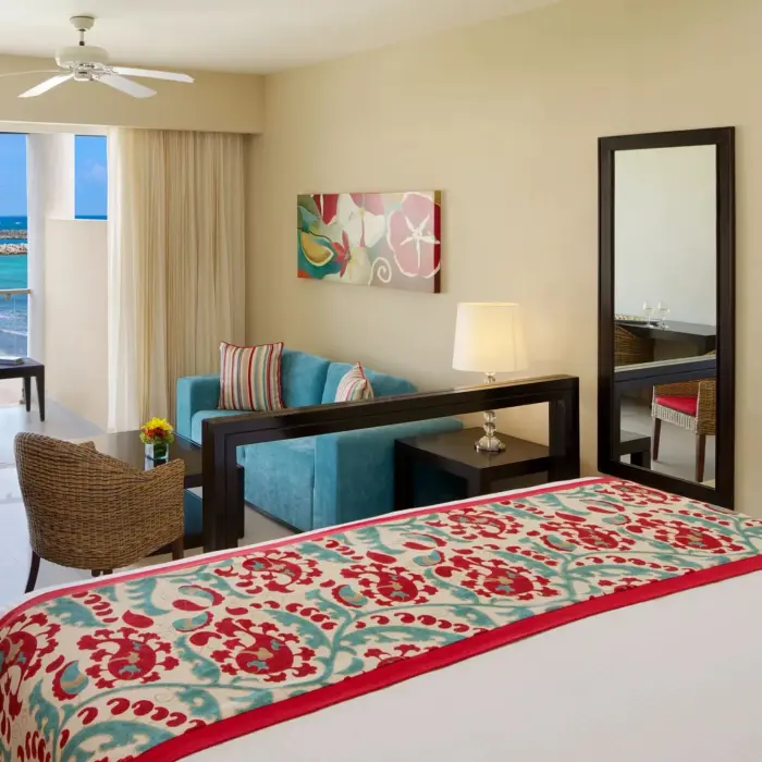 King suite with panoramic ocean view, private balcony, work desk, and cozy sitting area.