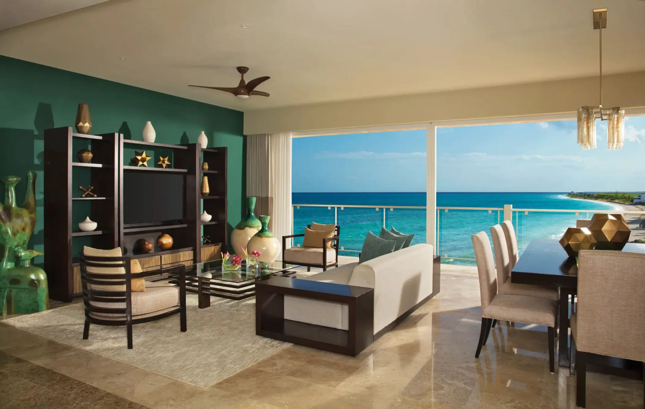 Spacious oceanfront living and dining area with modern decor, full wall window, and views of the Caribbean Sea.