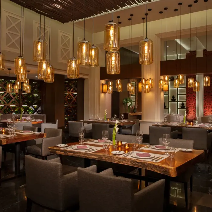 Elegant dining room at Tamarindo with warm lighting, wooden tables, and amber glass pendant lights for fine dining.