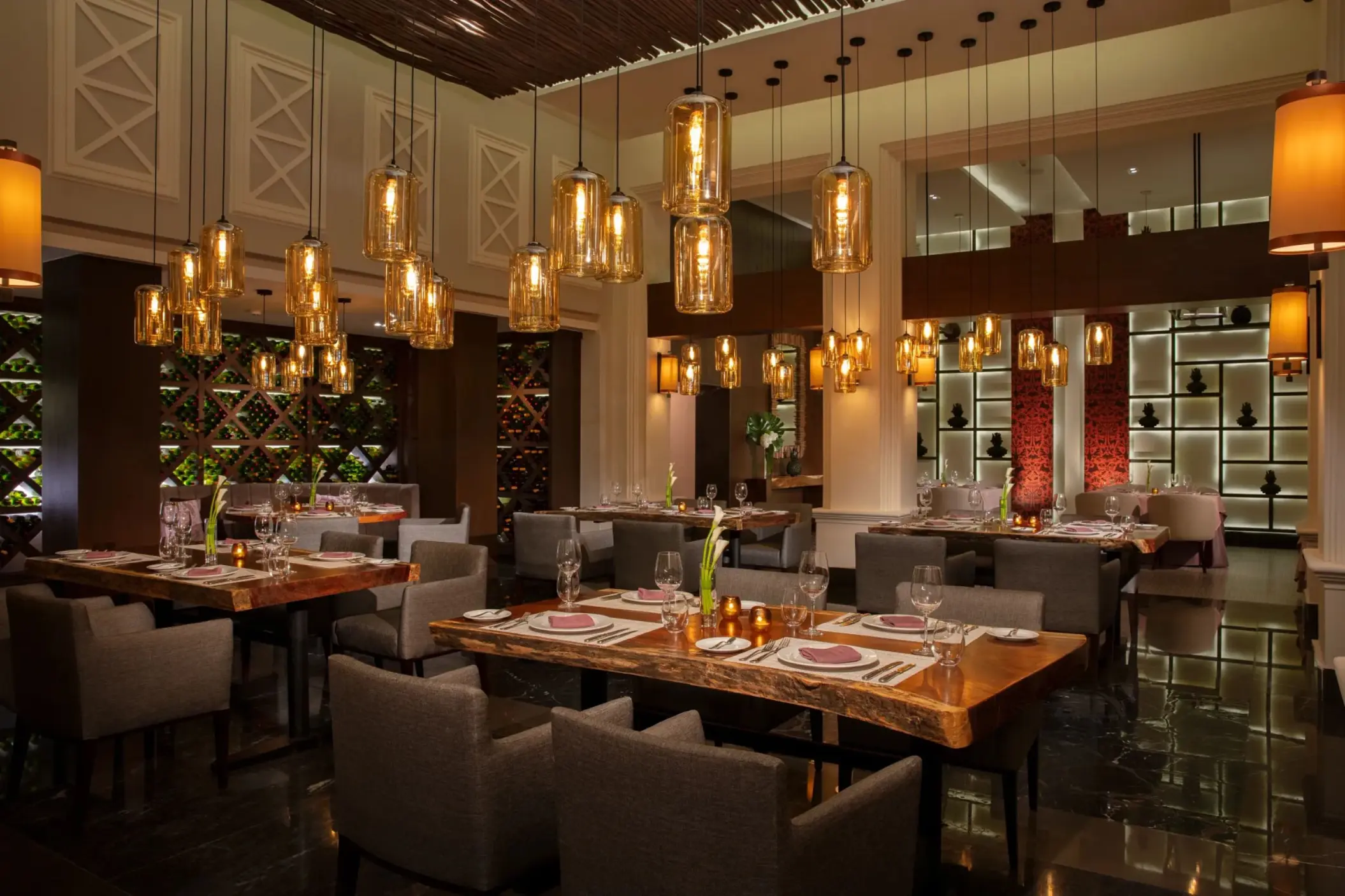 Elegant dining room at Tamarindo with warm lighting, wooden tables, and amber glass pendant lights for fine dining.