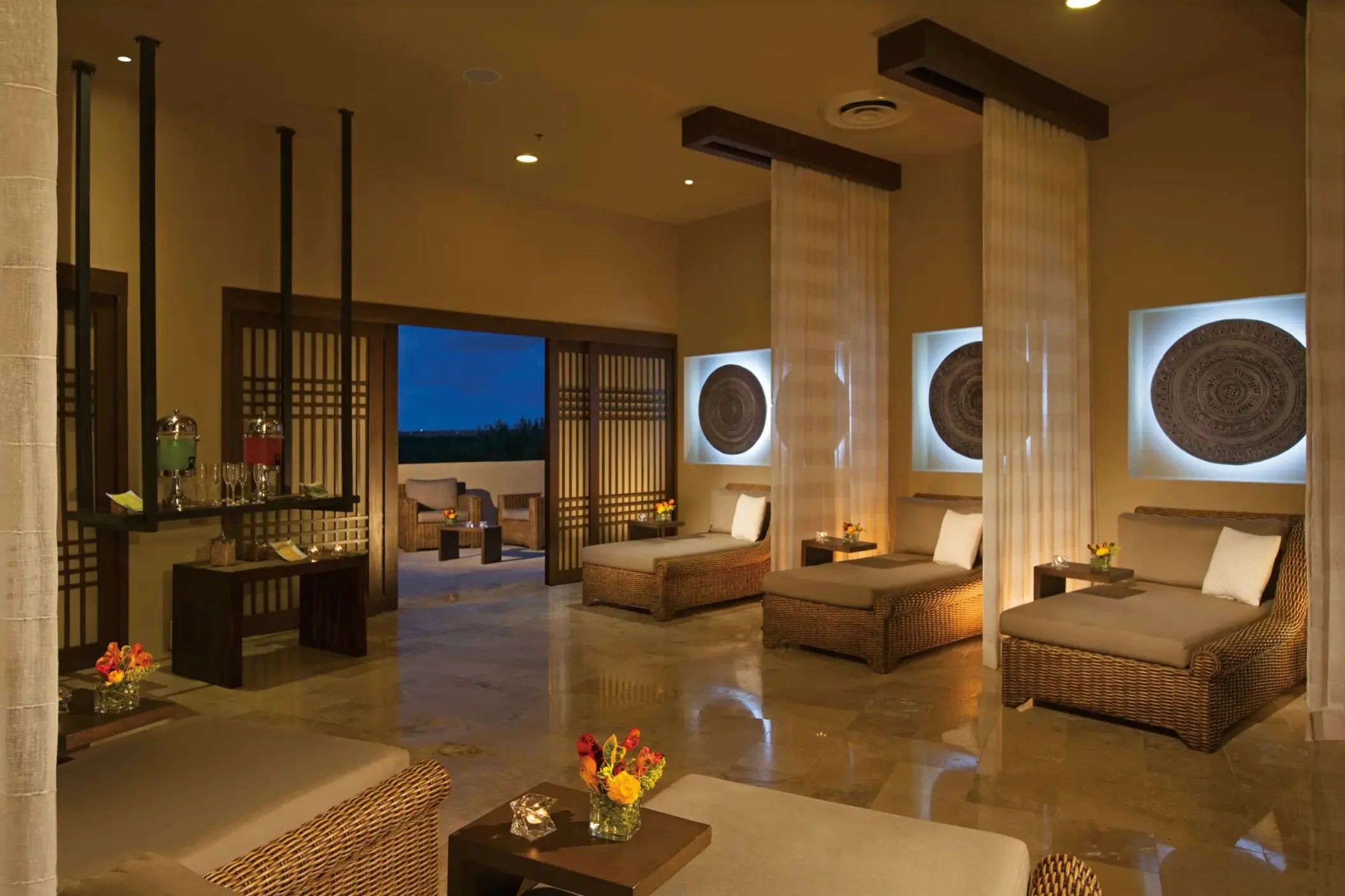 Serene spa relaxation lounge with wicker chairs, soft lighting, and open-air terrace for a peaceful retreat.
