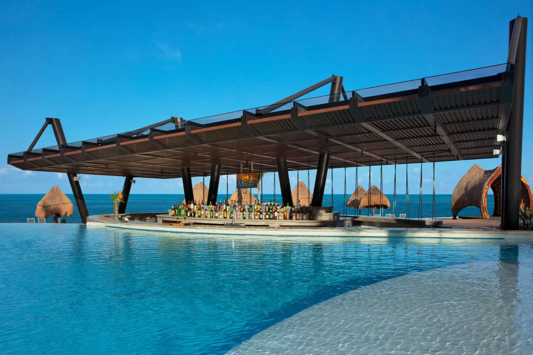Poolside swim-up bar with tropical thatched-roof accents, offering ocean views and an extensive drink selection.