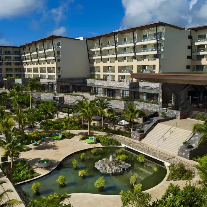 Resort garden area with tropical landscaping, a central fishpond, and surrounding lush palm trees.