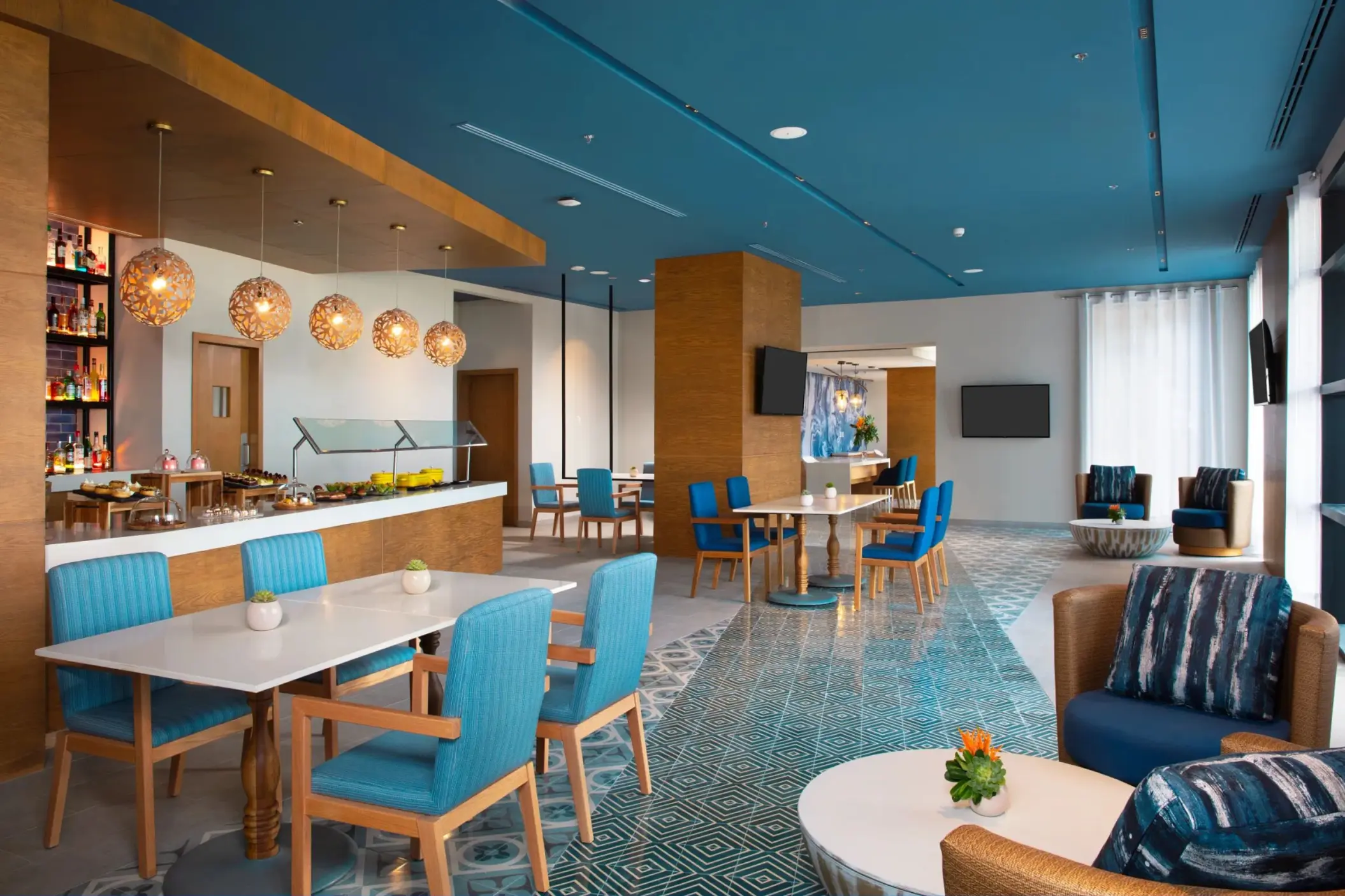 Bright and modern lounge with blue and wood decor, buffet area, and cozy seating ideal for relaxing or dining.