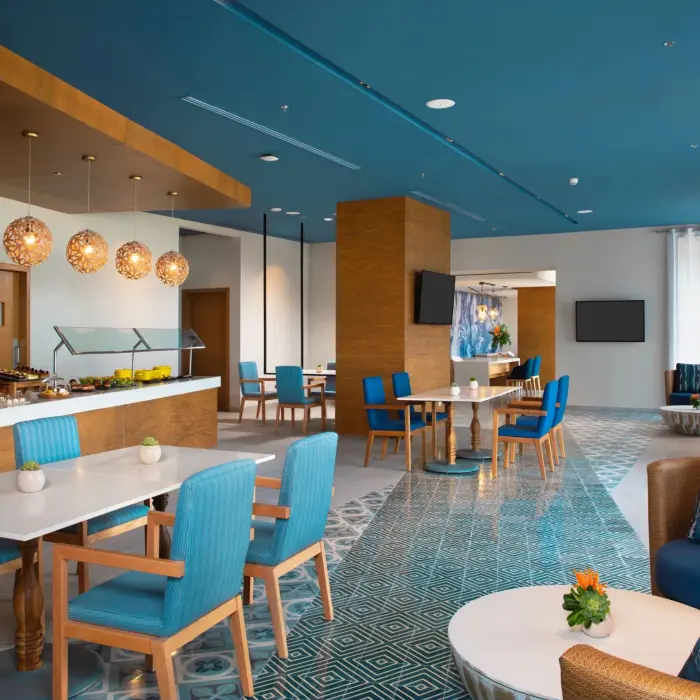 Bright and modern lounge with blue and wood decor, buffet area, and cozy seating ideal for relaxing or dining.
