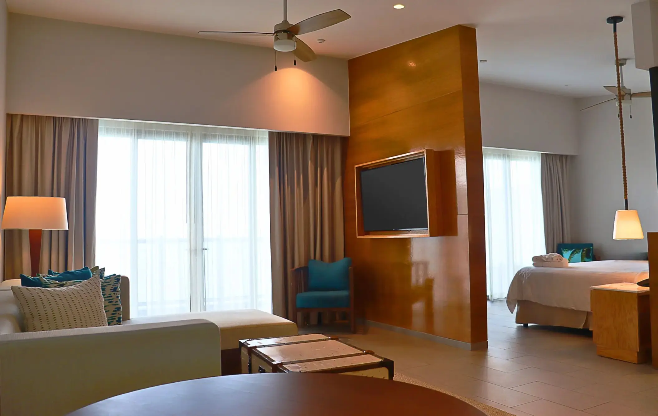 Spacious master suite with separate living and sleeping areas, wood divider wall, and floor-to-ceiling curtains.