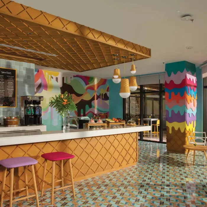 Bright café with waffle-cone inspired design, pastel seating, and artistic wall decor.