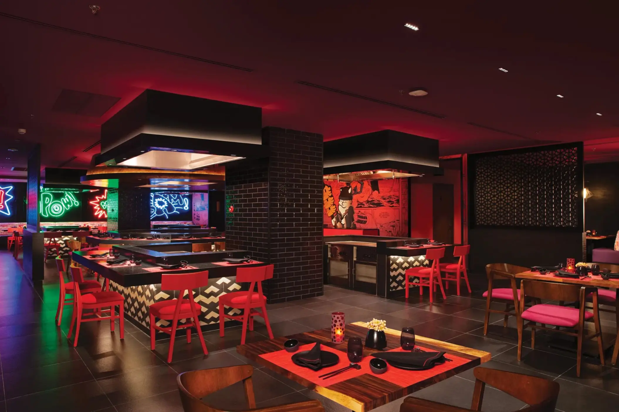 Modern Asian restaurant with teppanyaki grills, red and black décor, and neon wall art.