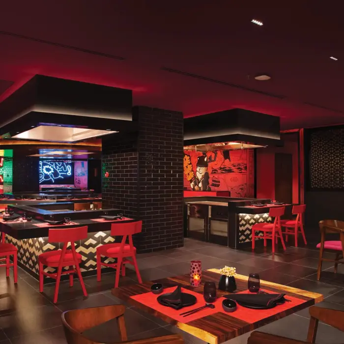 Modern Asian restaurant with teppanyaki grills, red and black décor, and neon wall art.