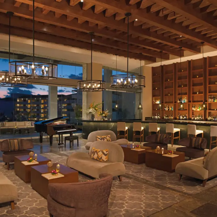 Interlude lobby bar with plush seating, piano, high ceilings, and wall-to-wall bar display.