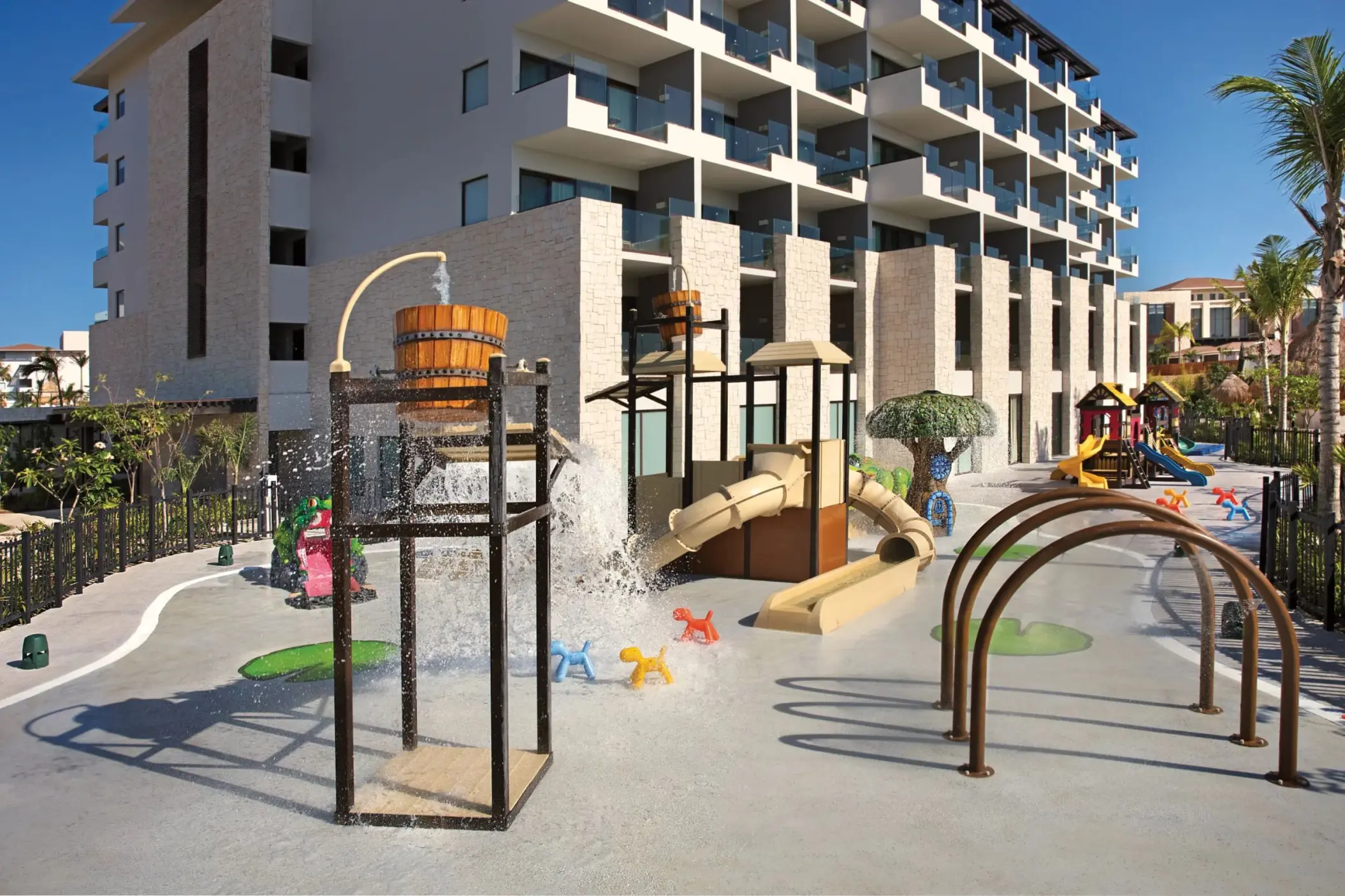 Outdoor Explorer’s Club play zone with splash bucket, slides, and colorful animal-themed spray features.
